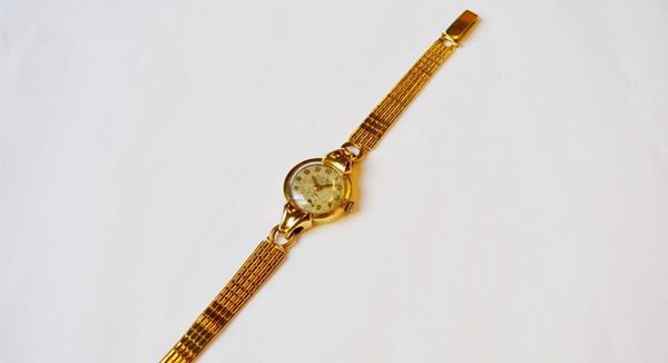 Orologio da polso per signora Delbana Watch, anni '50, in oro giallo 18 kt  Cassa con fondello a scatto, anse trangolari scanalate. Quadrante argentÃ¨   con numeri arabi applicati, secondi ad ore sei, lancette a spada oro.       Movimento a carica manuale. Bracciale a nastro in oro giallo. Diam. mm 22,  quadrante ossidato