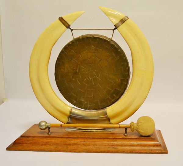 Gong sorretto da due corni di ippopotamo uniti da guarnizioni in argento inglese, base in legno, alt. cm 47