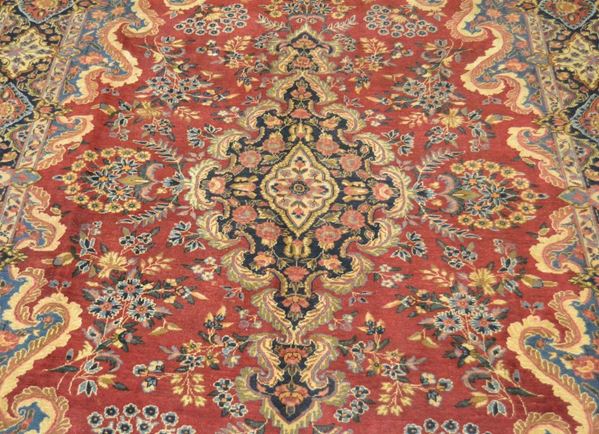 Tappeto persiano YAZD, del 1930 circa, fondo rosso a motivo floreale, con medaglione centrale e bordura blu, cm 365x255