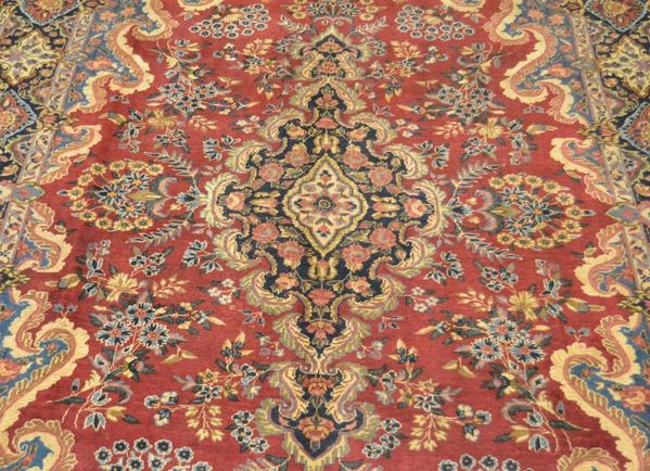 Tappeto persiano YAZD, del 1930 circa, fondo rosso a motivo floreale, con medaglione centrale e bordura blu, cm 365x255