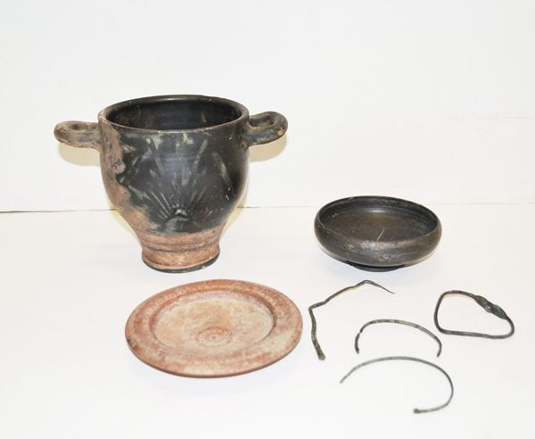 Lotto di oggetti etruschi   Materia e tecnica: argilla figulina arancio, impasto buccheroide bruno, bronzo; vernice nera lucente e vernice rossa, eseguiti a tornio veloce  Skyphos a vernice nera con labbro rettilineo e corpo ovoide, piede a disco, anse a bastoncello impostate obliquamente sullâ€™orlo, decorato in bianco con motivo a palmetta e due fasce parallele in paonazzo; piattello cerretano con labbro pendulo e orlo arrotondato, vasca troncoconica poco profonda, piede a disco, decorato sulla tesa e al centro con file di puntini; coppetta in bucchero su basso piede a disco; quattro frammenti in bronzo (7)   Produzione: ceramica etrusca  Stato di conservazione: integri   Dimensioni: alt. cm 15, diam. cm 13,5; alt cm 13,5, diam. cm 2,2; alt. cm  4,5, diam. cm 11,7   Datazione: VIII-VI sec. a.C.