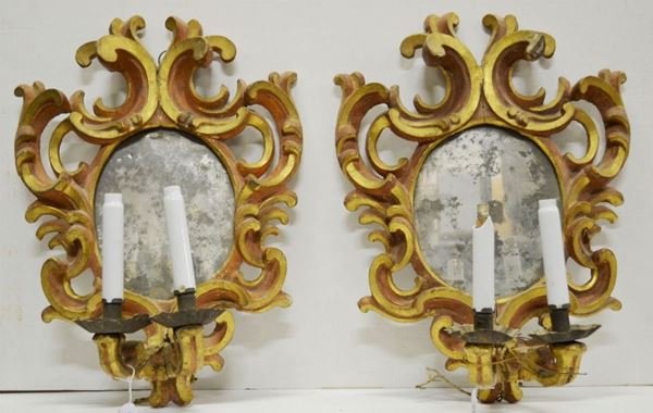 Coppia di specchiere a ventola, Toscana, prima metÃ  sec. XVIII, en suite   col lotto precedente, in legno intagliato, laccato rosso ed in parte dorato a grandi volute contrapposte, specchio ovale, complete di due braccetti    portacandele, cm 56x40, piccoli danni e mancanze