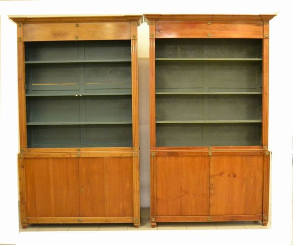 Coppia di librerie, Toscana sec. XX, in ciliegio, a due sportelli e tre ripiani, colonne scanalate e rapporti in metallo dorato, sportelli mancanti, cm 132x32x214 (2)
