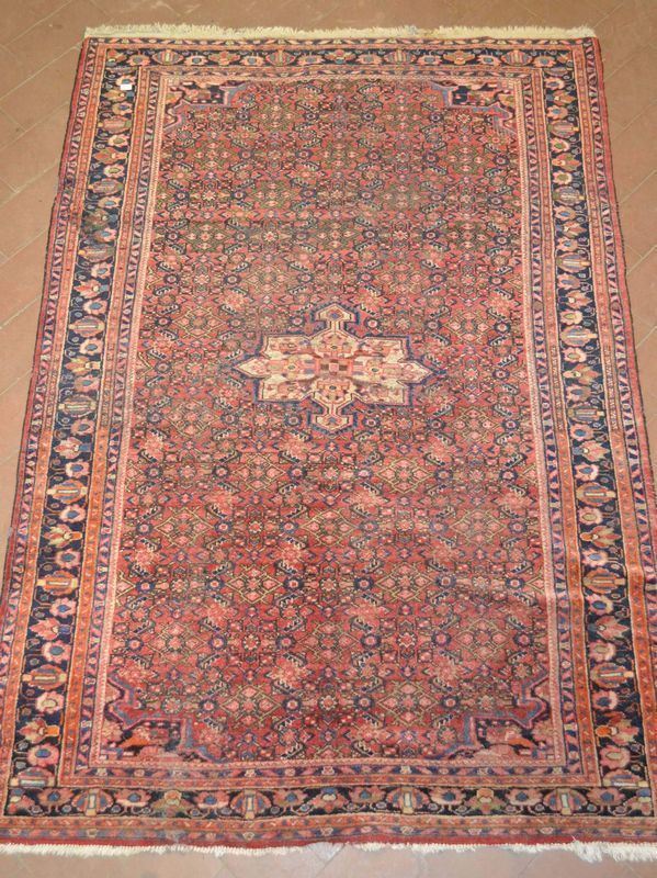 Tappeto fondo color salmone, campo decorato da motivi vegetali geometrizzanti, al centro piccolo medaglione sagomato, molteplici bordure, cm 222x154, consunto