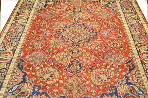 Tappeto persiano ISFAHAN fine di vecchia manifattura, fondo rosso a motivo floreale, con medaglione centrale e bordura blu e beige, cm 400x290