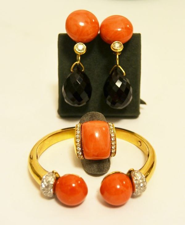 Bracciale rigido in oro giallo con finali di corallo e pavÃ¨ di brillanti, g 45,2; anello en suite con corallo e due file di brillanti, g 20,8; paio di orecchini con corallo, pendente in onice e due brillanti di ct 0,25 circa, g 42 (3)