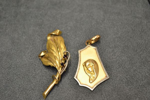 Medaglietta con immagine sacra in placca sagomata con maglia ovale, punzone 750; spilla a foglia cesellata in oro giallo e argento decorata con due granati. peso complessivo g 12 (2)