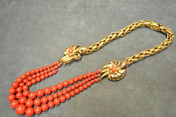 Collana in oro giallo e corallo la parte anteriore realizzata a tre fili di sferette in corallo rosso poste in gradazione trattenute alle estremita da due corolle stilizzate in oro giallo traforato centrate da piccoli coralli, la parte posteriore realizzata a maglie a sezione tubolare in oro giallo, g 89