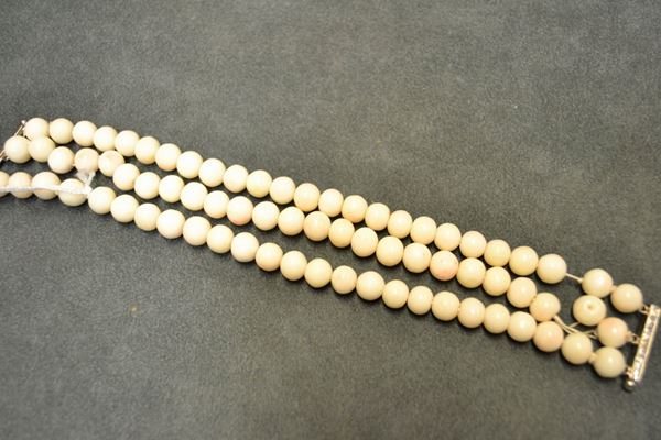 Bracciale in oro bianco e corallo bianco  realizzato a tre fili di sfere in corallo con fermatura cesellata, g 65, en suite con la collana