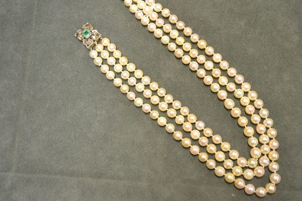 Collana di perle, in oro giallo, argento, smeraldo e diamanti realizzata a tre fili di perle di diam. mm 8,5 a mm 10, con fermatura decorata da smeraldo centrale taglio a gradini al centro di una placca con motivi a foglie decorati da rose di diamanti, g 152