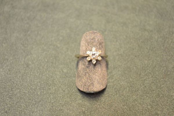 Anello in oro bianco e diamante lavorato come un fiore con brillante centrale di ct 0.30 circa entro sei petali decorati con piccoli brillanti, g 2