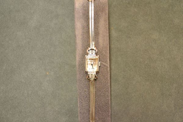 Orologio per signora Pery, in oro bianco 14 Kt e diamanti, cassa rettangolare con fondello a scatto, anse decorate da piccoli brillanti, vetro bombato. Quadrante Argente' con numeri arabi e indici puntiformi. movimento a carica manuale. Bracciale in oro bianco lavorato a  maglia morbida e chiusura regolabile a scatto. Diam. cm 19x14