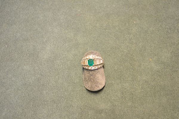 Anello in oro bianco, smeraldo e diamanti disegnato come una fascia sagomata decorata da due linee in brillanti e da un linea di diamanti baguette posti in gradazione al centro della quale Ã¨ montato uno smeraldo ottagonale, punzone 750, g 7