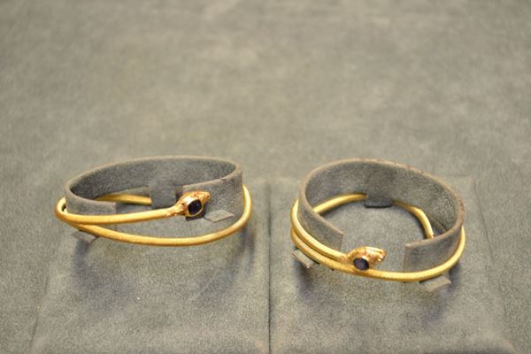 Due bracciali in oro giallo, zaffiri e rubini a forma di serpente cesellato, testa decorata con uno zaffiro a cuscino e occhi in piccoli rubini cabochon, g 24 complessivi (2)