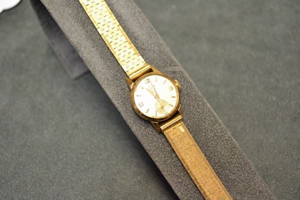 Orologio da polso per signora Kismet, in oro giallo 18 kt Cassa in oro rosa con fondello a scatto. Quadrante champagne con indici applicati a bastone e numeri arabi. Movimento a carica manuale. Bracciale in oro giallo a maglie satinate. Diam. mm 21