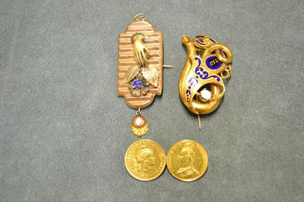 Gruppo di tre spille in oro 18 kt e a basso titolo, smalti, vetro, opale rispettivamente realizzate: con moneta sterlina e pesos argentino in oro giallo poste in linea, g 17; a placca sagomata con mano e fiori in rilievo, g 8; a volute intrecciate cesellate e decorate in smalto blu e piccolo opale, g 13, lievi danni ai restauri