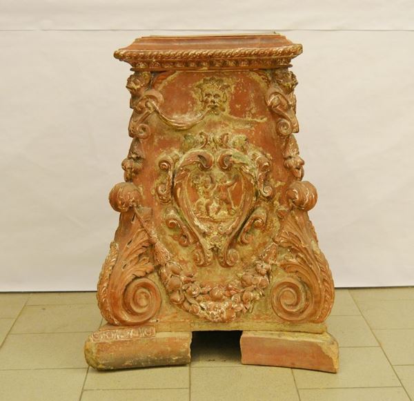 Base per stufa, sec. XIX, in terracotta lavorata a foglie e figure, cm 74x52x98, rotture