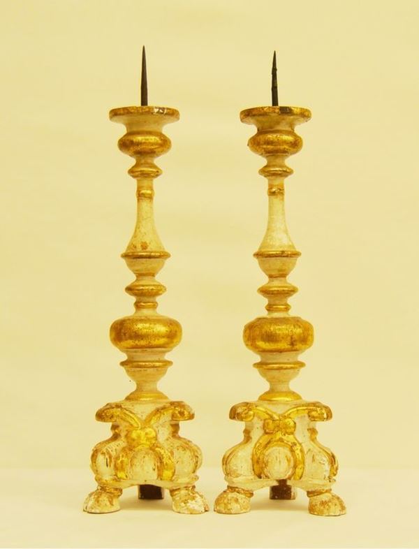 Coppia di candelieri, sec. XVIII, in legno laccato e dorato, base su piedi a zampa di capra, alt. cm 70 ( 2 )