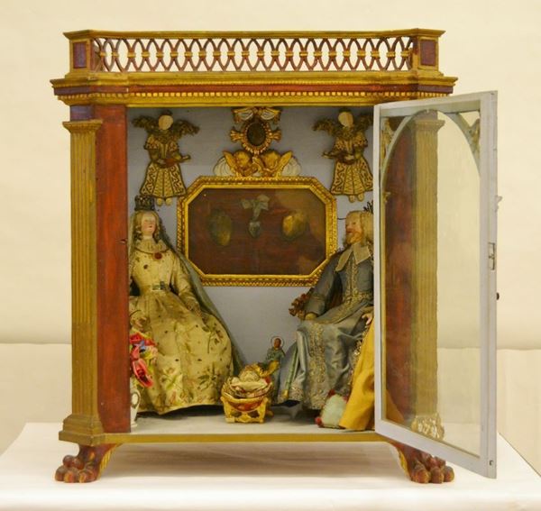 Presepe, Siena, sec. XVIII, composto da quattro personaggi in legno e cera, all'interno cornice dorata  decorata a putti contenente tre reliquie, cm 74x50x79