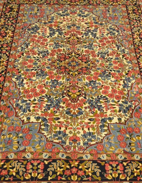 Tappeto persiano KIRMAN LAVAR, fondo beige, campo a motivo floreale multicolore con medaglione centrale e bordura blu e beige, con cantonali celesti, di vecchia manifattura, cm 306x202