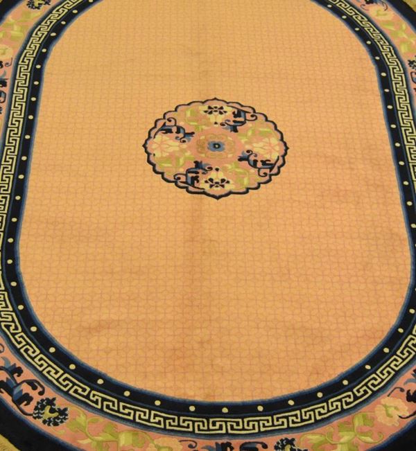 Tappeto cinese fine, a forma ovale, fondo color salmone in tinta unita, con motivi geometrici, bordura blu e rosa con motivo vegetale, cm 248x171