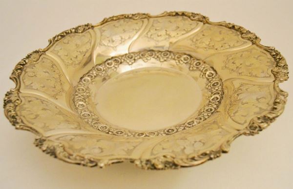 Vassoio ovale in argento cesellato con bordo sagomato, tre piedini, gr 590, diam. cm 29