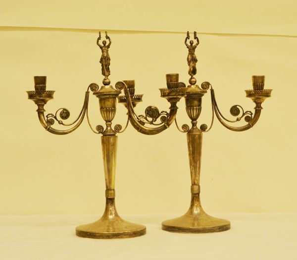 Coppia di candelieri, sec. XIX, in argento lavorato, a due fiamme, con sovrastante la Dea della Vittoria, alt. cm 38, g 1615, rotture ( 2 )