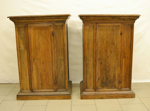 Coppia di credenzini a colonna, in noce, ad uno sportello, piano a becco di civetta, base a ciabatta, cm 76x50x109, ricostruiti con materiale antico, difetti