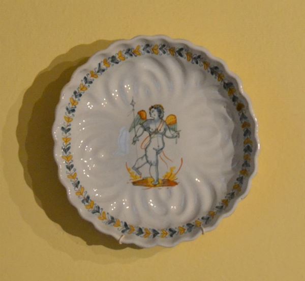 Alzata, Firenze, sec. XVIII, in maiolica decorata con al centro PUTTO, diam. cm 25