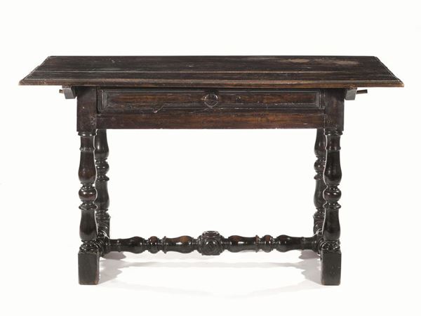 Tavolo, Emilia, metÃ  secolo XVII, in noce a patina scura, piano rettangolare con becco di civetta, un cassetto nella fascia, gambe tornite a balaustro riunite da traverse a rocchetto, piedi a dado, cm 128x67x73, piccoli danni