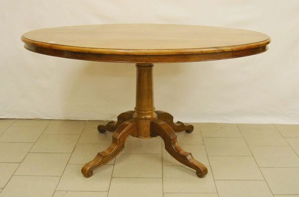 Tavolino, sec. XX, in castagno, piano ovale su fusto centrale tornito, quattro piedi mossi, cm 150x104x80