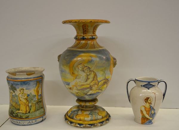 Albarello, sec. XIX, in maiolica dipinta, raffigurante il sacrificio di Abele, alt. cm 25, diam. cm 18; brocchetta, sec. XIX, in maiolica dipinta,  a due manici, raffigurante S. Giovanni Battista, alt. cm 21,5 e vaso, sec. XIX, in maiolica dipinta, raffigurante Tritone e Ninfa, reca due appliques a testa di montone, alt. cm 46,5 (3)