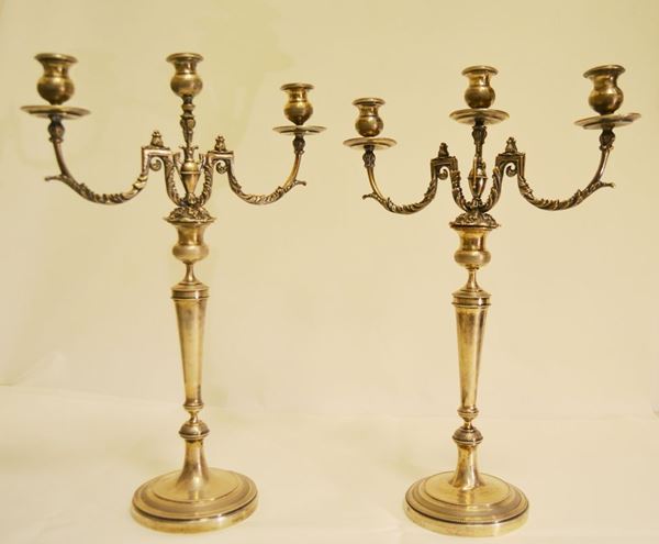 Coppia di candelieri in argento lavorato, a tre portacandele ciascuno con basi appesantite (uno da restaurare) alt. cm 44