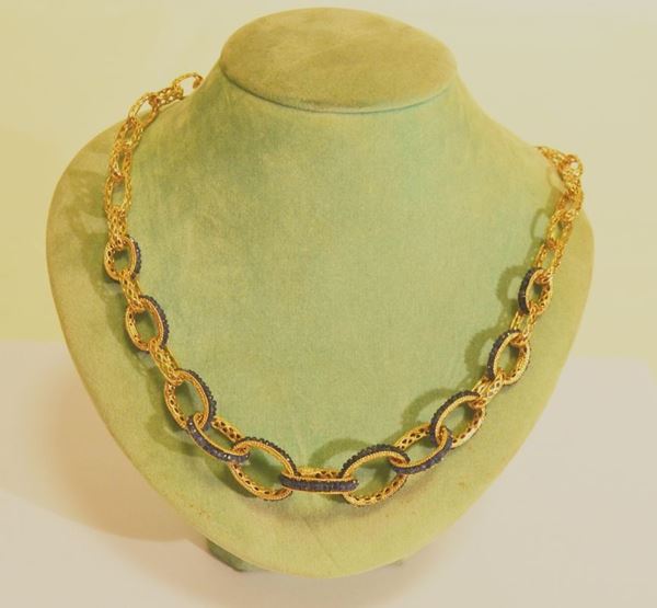 Collana, in oro giallo a grosse maglie intrecciate e traforate con finale a maglie decorate a zaffiri, g 38,8