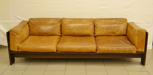 Divano, anni '70, produzione Cassina, a tre posti, fusto in noce, cuscini in pelle marrone, cm 209x75,5x66