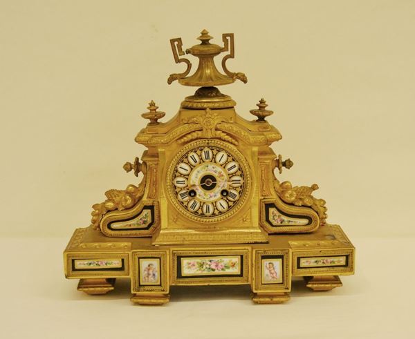 Orologio da tavolo, Parigi epoca Carlo X, prima metÃ  sec. XIX, in bronzo dorato, quadrante e placchette in porcellana di Sevres a motivo floreale, sormontato da un vaso a due anse, alt. cm 32, meccanismo con scappamento ad ancora, sospensione a lamina di acciaio con registratore per le piccole differenze brevetto Brocot situato alle ore 12 del quadrante, carica 8 giorni, suona le ore e le mezze ore, da revisionare e cassa da restaurare