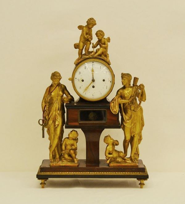 Orologio da tavolo, fine sec. XIX, mostra in metallo su base in legno, decorato a ANGELI E DEE in legno dorato, alt. cm 53