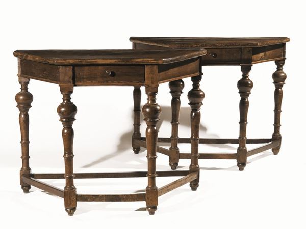 Coppia di tavoli a muro, Toscana, inizi sec. XVIII, in noce a patina scura, piano sagomato, un cassetto nella fascia, gambe tornite a balaustro riunite da traversa, piedi a cipolla; i due mobili formano uniti un piccolo tavolo  esagonale, cm 107x56x83, alcuni danni e restauri