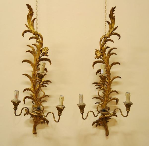 Coppia di appliques a tre bracci, in stile Settecento, in legno dorato e    intagliato a motivo vegetale, alt. cm 90, danni