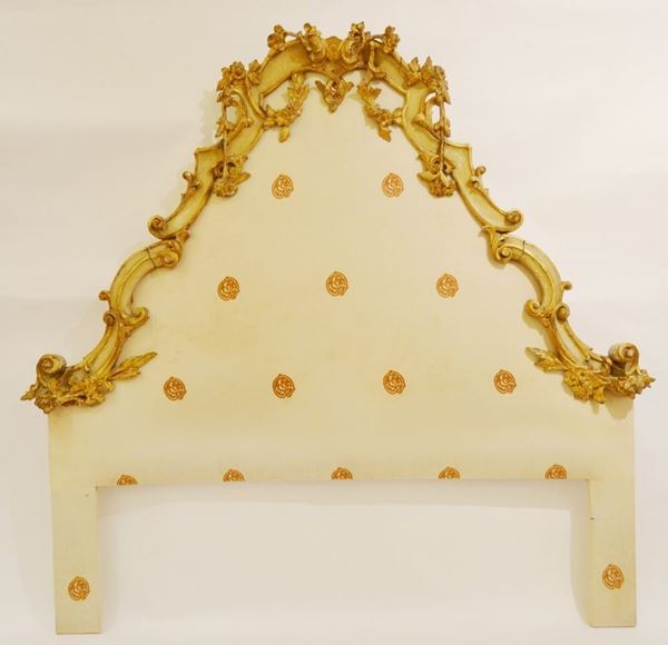 Testiera di letto in stile Veneto del Settecento, in legno intagliato e dorato di forma sagomata a volute con fiori e foglie ricadenti, cm 166x180