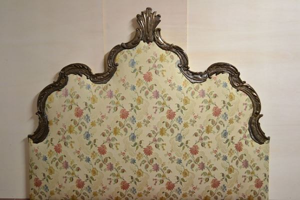 Testiera di letto, sec. XVIII, con cornice in rame sbalzato e argentato sormontata da cimasa a palmetta ed imbottita in seta operata a fiori, cm 184x147