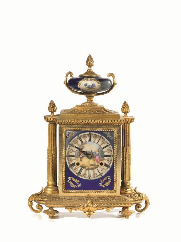  Orologio soprammobile,  in stile Settecento, in metallo dorato e placchette di porcellana, fiancheggiato da colonne in forma di tempietto su basamento rettangolare ansato sormontato da vasetto, quadrante con numeri romani e scena galante, alt. cm 33,5,  danni, meccanismo da revisionare 