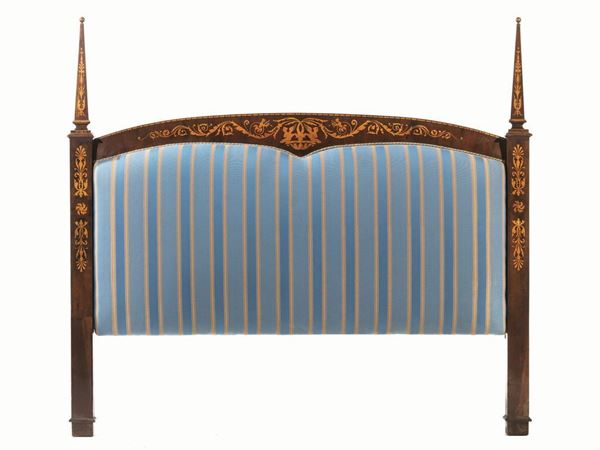  Testiera di letto, sec. XIX, in stile Carlo X,  in noce intarsiato in acero, di forma centinata, elementi laterali a obelisco intarsiati con grandi volute di foglie di acanto, arpie e figure fantastiche, ricoperta in cotone a righe azzurro, lung. cm 175