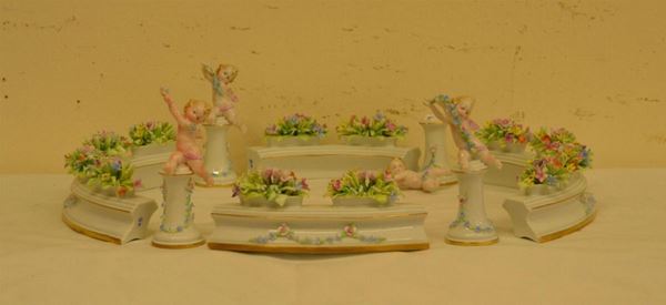  Centrotavola, fine sec. XIX, in porcellana Ginori, composto da quattro piccoli putti e quattro alzatine decorate a motivi floreali, difetti e mancanze 