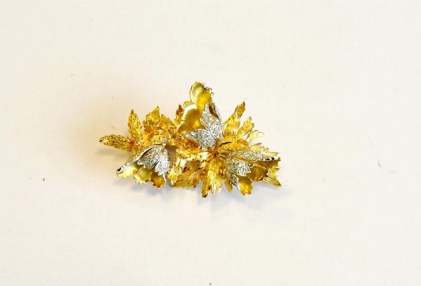 Spilla in oro giallo, oro bianco e diamanti modellata a tralcio fogliaceo in oro satinato con fiori decorati in diamanti huit huit, punzone oro 750, g 13                                  