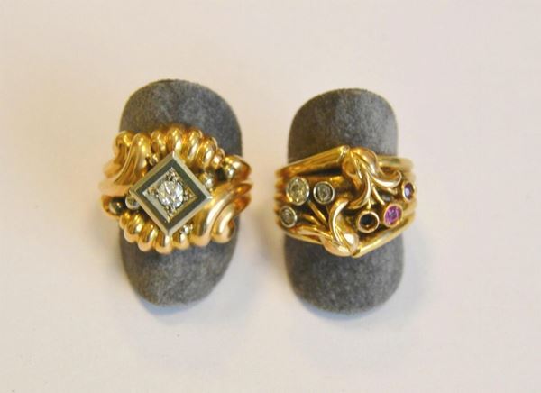 Due anelli in oro giallo, rubini e diamanti, rispettivamente a fascia rigata con rubini e rose e a fascia a volute con piccolo brillante al centro, g 20 , un rubino mancante   (2)                                                                                                                      