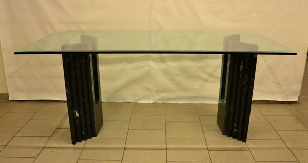 Tavolo, anni â€™80, piano in cristallo poggiante su due basi in marmo sbalzato, cm