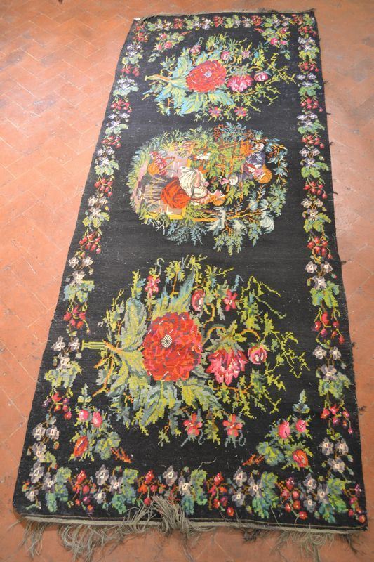  Tappeto russo,  fondo nero, al centro due fanciulli entro elementi floreali, cm 421x169,  consunto 