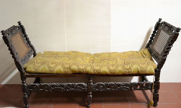 Divanetto a panchetta, sec. XIX, in noce intagliato a patina scura,        