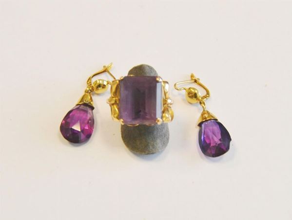 Anello e paio di orecchini pendenti in oro giallo e ametiste, ciascun orecchino realizzato come una semisfera in oro liscio a cui â”œÂ¿ sospesa un'ametista briolette; l'anello con ametista rettangolare montata a griffe affiancata da due motivi a fiocco, g 16 complessivi   (difetti)   (3)